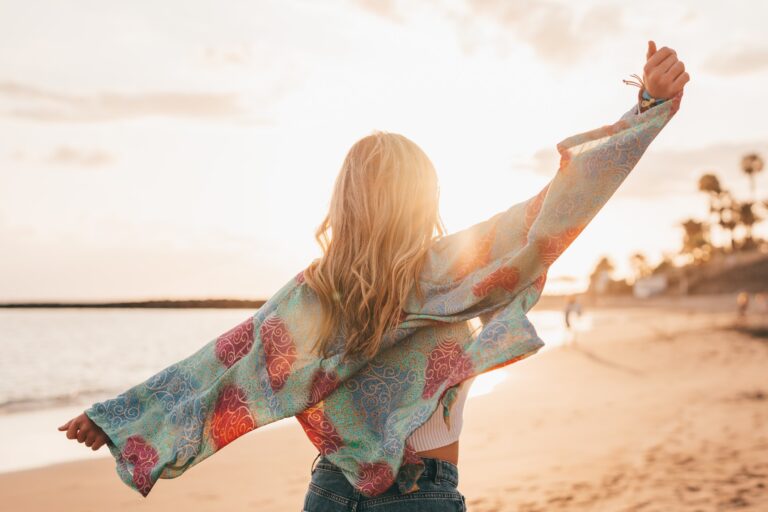 woman with arms stretched walking on the beach