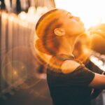 a woman looks to the sky as a light glows around her head