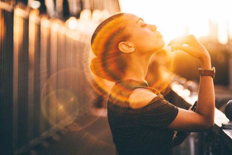 a woman looks to the sky as a light glows around her head