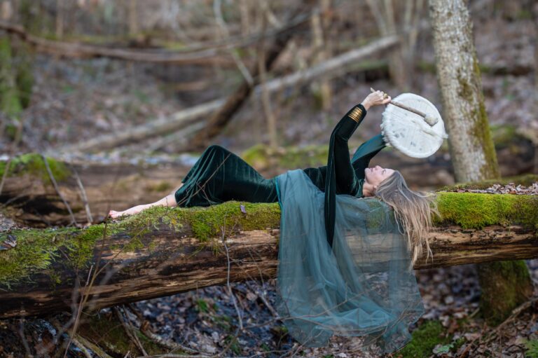 a woman lying on a log beating a drum