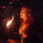 a woman holding a fire torch in the night