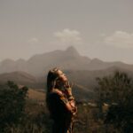 A woman looks up at the sky with mountains in the background