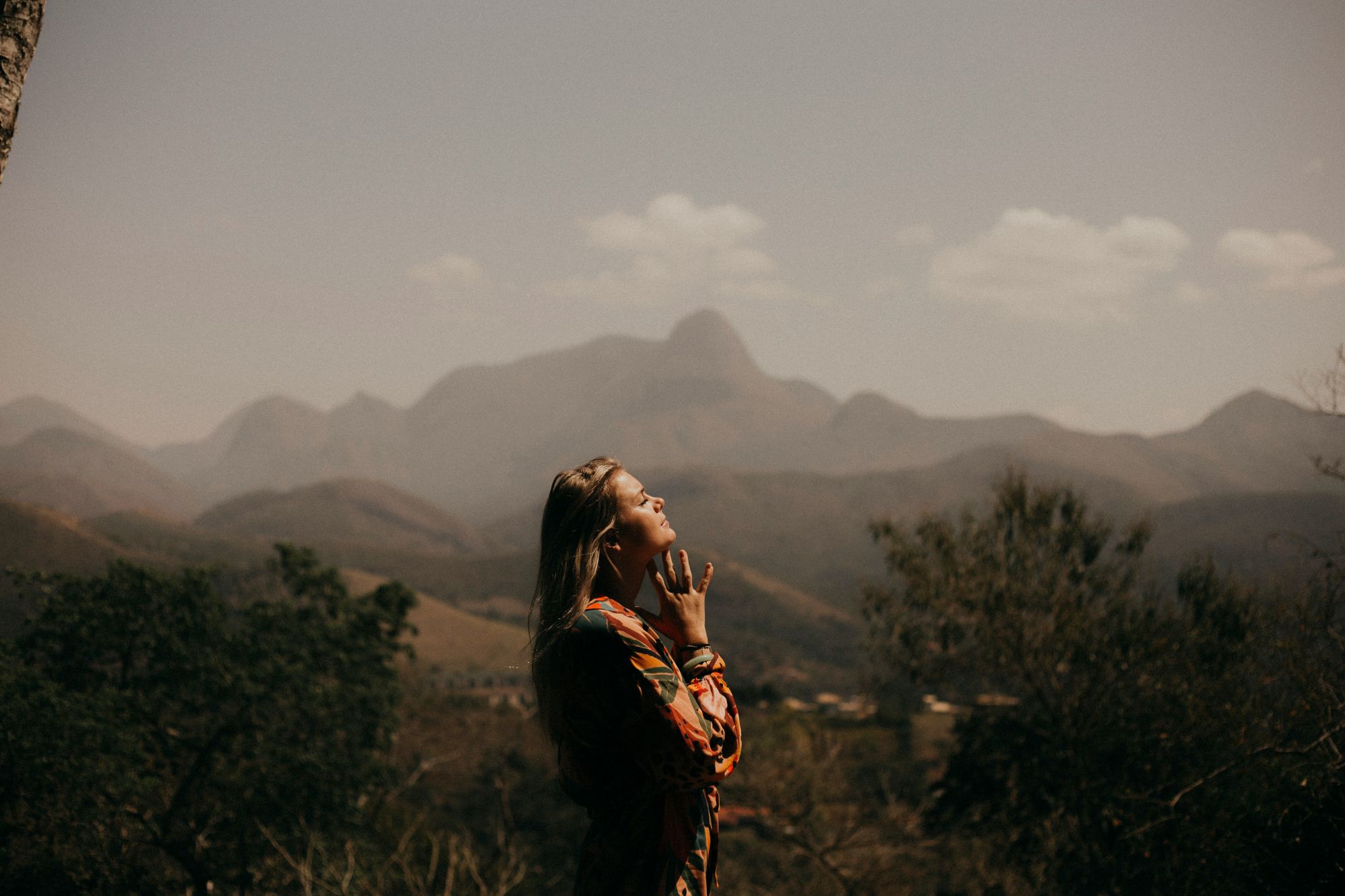 A woman looks up at the sky with mountains in the background
